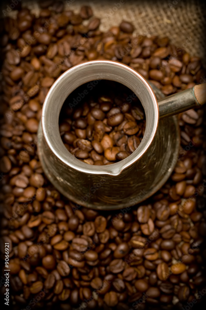 Fototapeta premium Cezve with freshly roasted coffee beans on sackcloth