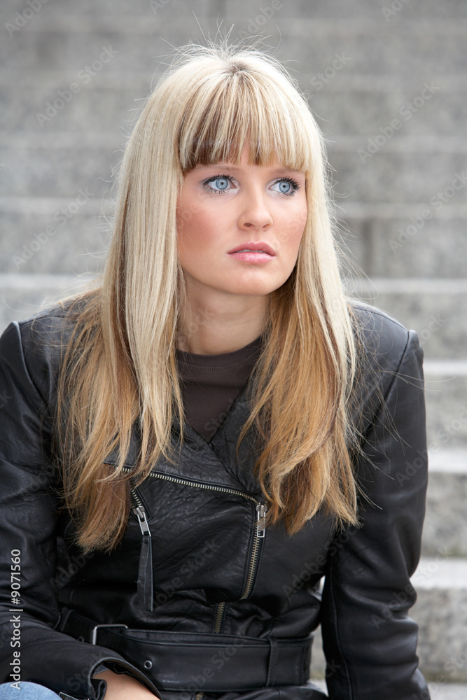 Young woman sitting on stairway, looking away, portrait Young woman sitting on stairway, looking away, portrait