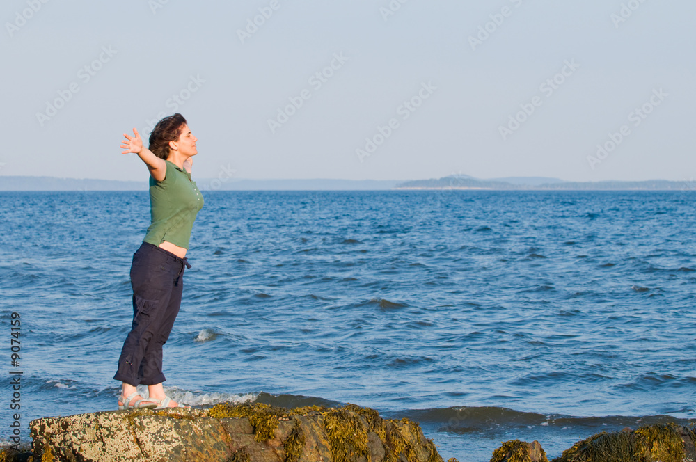 Young brunette woman at the beach with arms outstretched Young brunette woman at the beach with arms outstretched