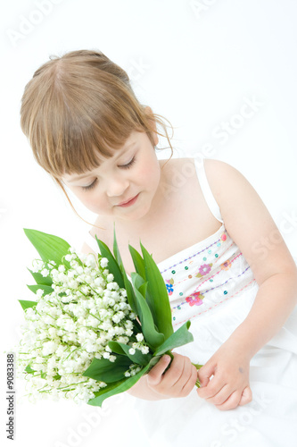 little, pretty girl holding bunch of lilies of the valley