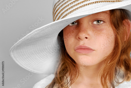 Φωτογραφία Young freckle faced girl with serious look wearing big hat