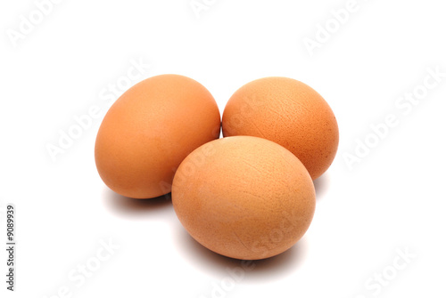 Three chicken eggs on a white background largly