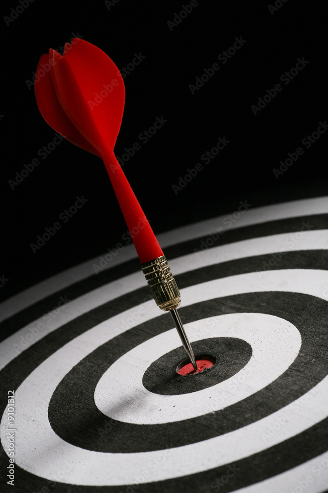 Portrait shot of a Red dart on bull's eye of a dart board Portrait shot of a Red dart on bull's eye of a dart board