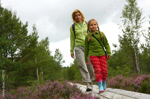 Mother and daughthter walking on  plank-way in forest