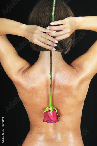 girl hold rose on naked back. black background