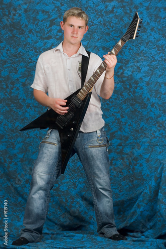 A young guitar player on a blue background playing the guitar