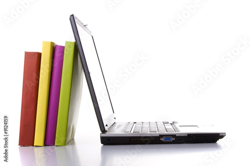 a laptop next to a stack of colorful books