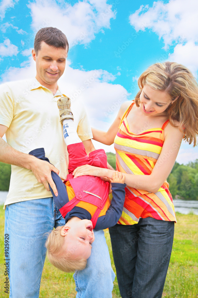 Fototapeta premium Parents hold child beneath by head