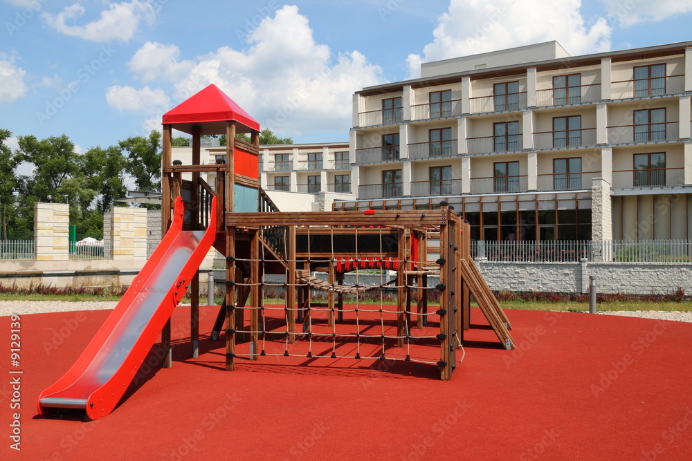 Playground with red slider in a front of modern building