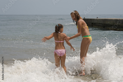 two girls of teenager make merry during a gale at the  seaside
