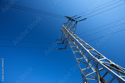 Steel electricity pylon on bright blue sky