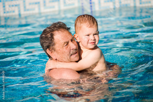 Grandfather and grandson swimming together in the pool. © nyul