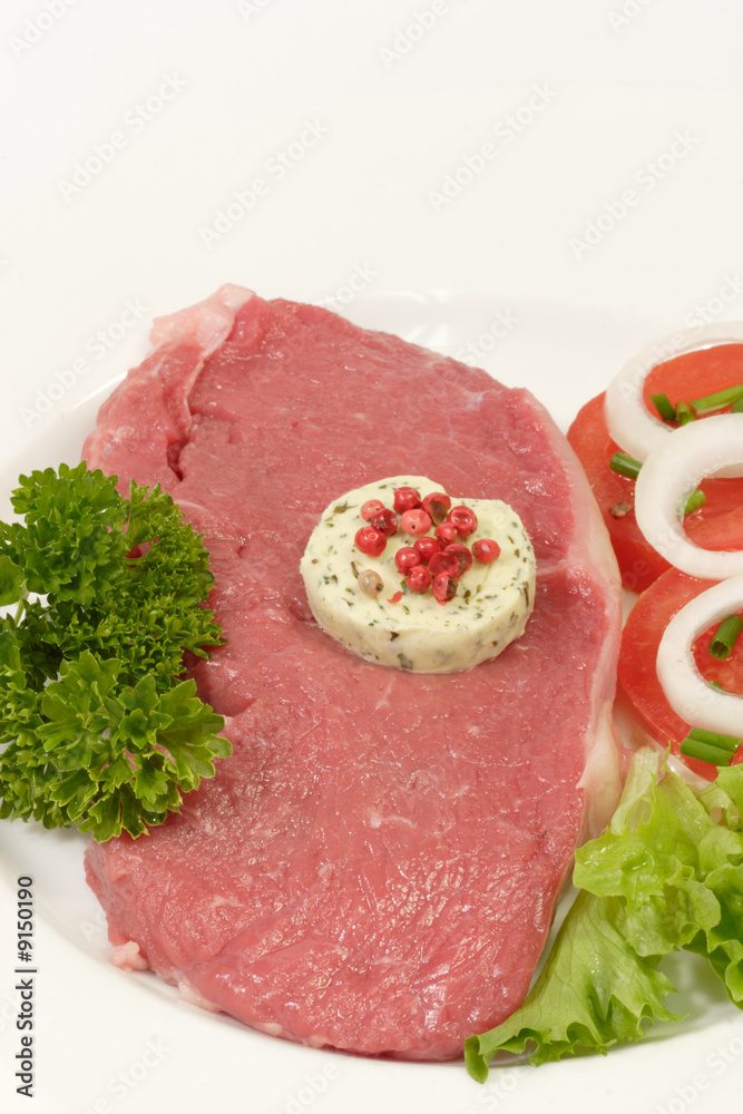 Rohes Rindersteak mit Garnierung auf hellem Hintergrund Rohes Rindersteak mit Garnierung auf hellem Hintergrund