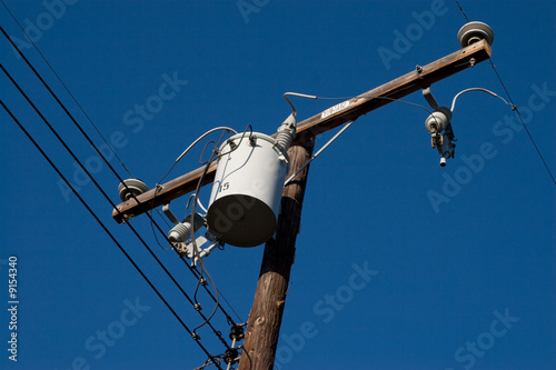 A power transformer on a wooden pole with wiring