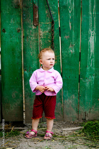 Portrait of a litle girl near green fence