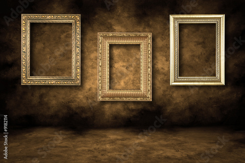 Three Guilded Picture Frames Hanging on a Grungy Wall photo