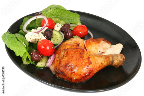 Roast chicken with a Greek salad, on a black plate