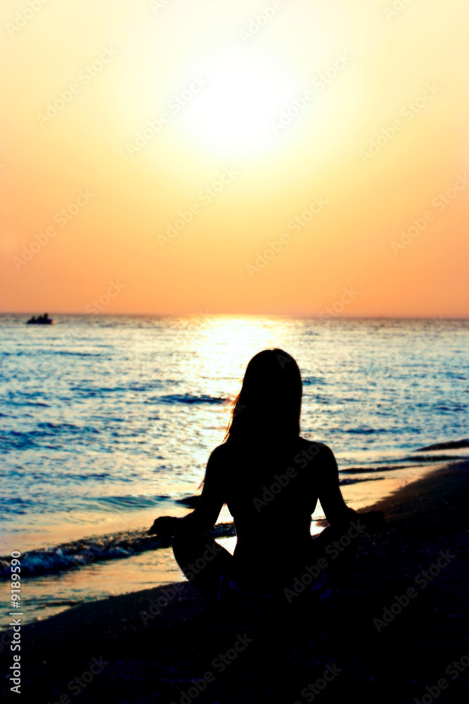 silhouette of young girl meditating on beach