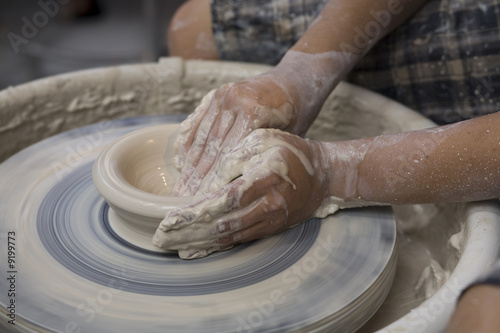 A potter works on a bowl on a potter's wheel