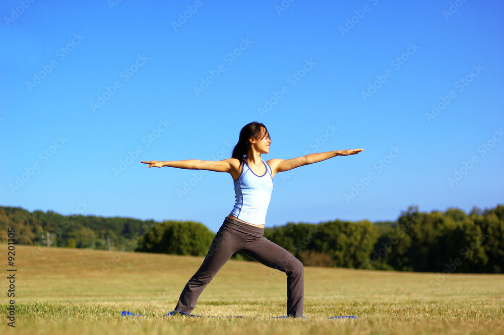 Girl practicing yoga in a summer meadow.