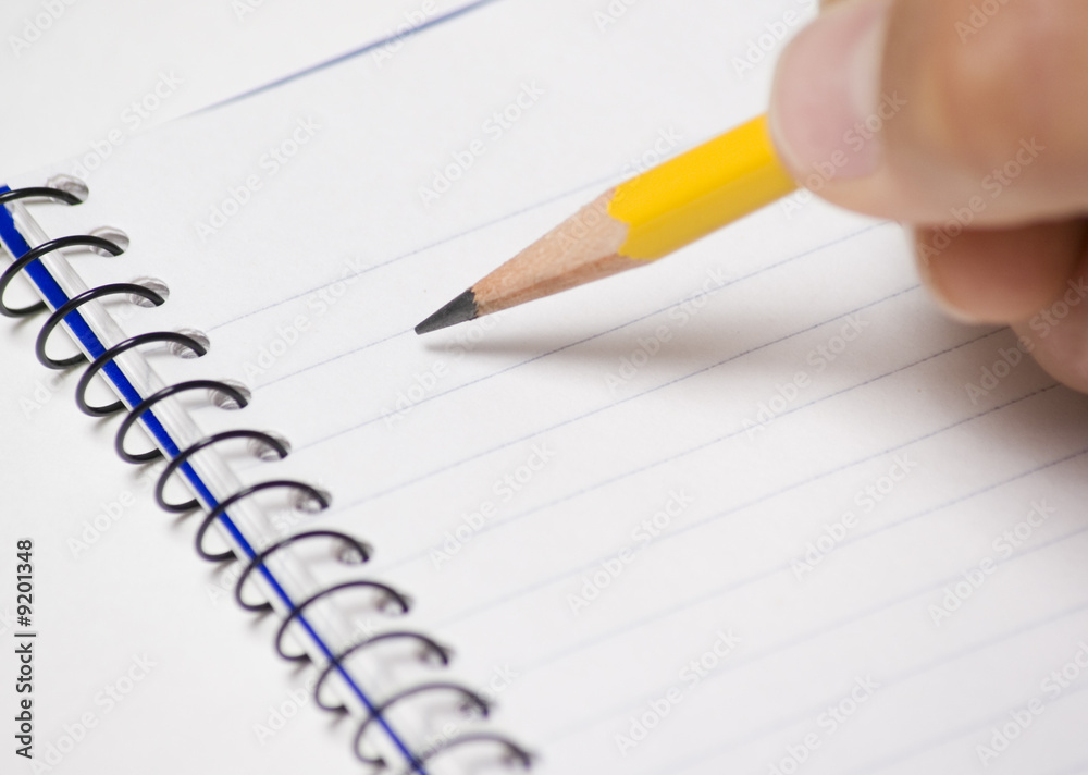 Note pad with pencil being held by a person Note pad with pencil being held by a person