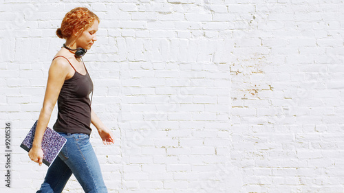 Attractive urban girl against white brick wall.
