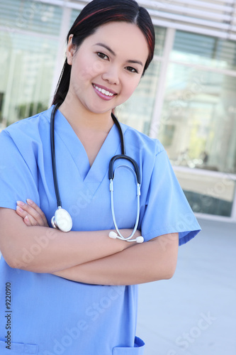 A pretty young asian woman nurse in front of hospital