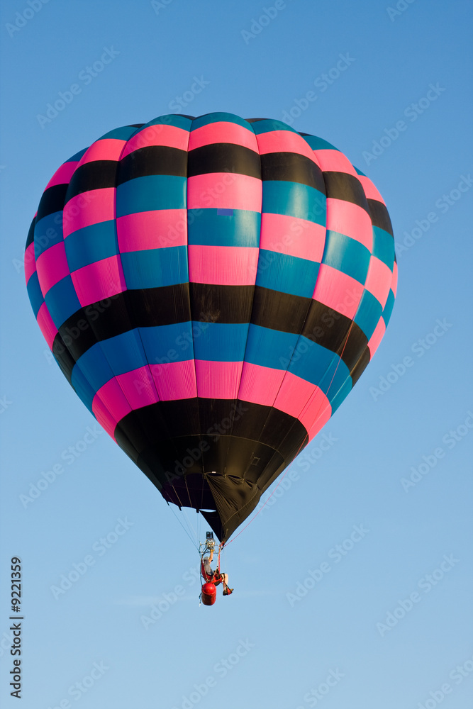 Fototapeta premium Colorful hot air balloon at festival mid-air on a clear day.