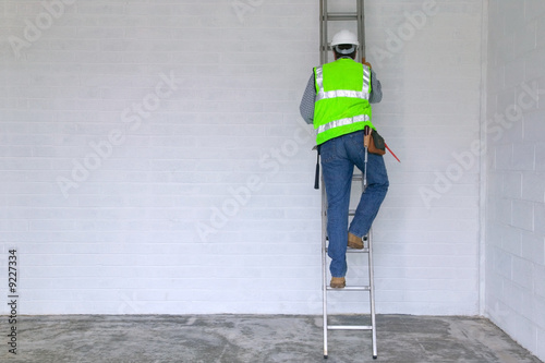 Workman in reflective vest and hard hat climbing a ladder