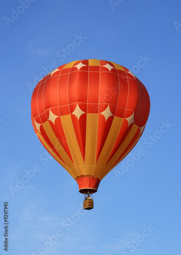 Red and orange hot air balloon in the blue sky.