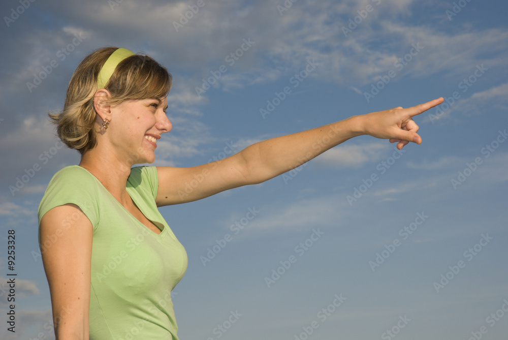 One young girl pointing somewhere on a blue background One young girl pointing somewhere on a blue background