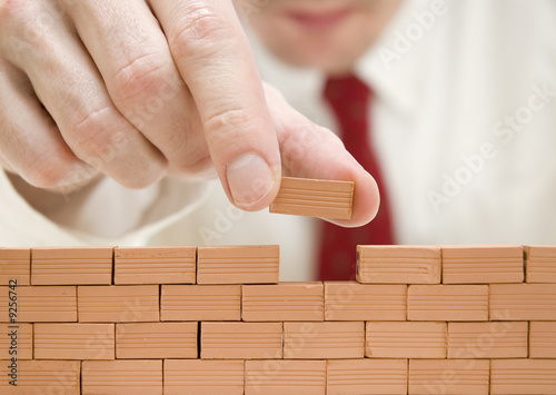 hombre de negocios construyendo un muro photo