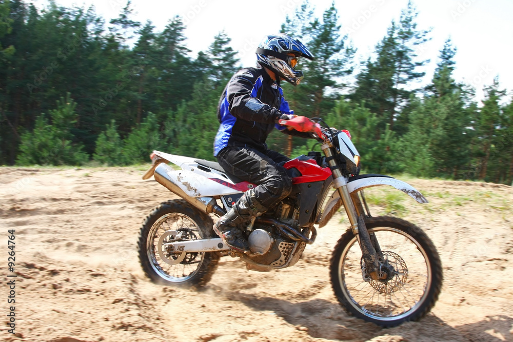 Man driving off-road motorbike in sand.