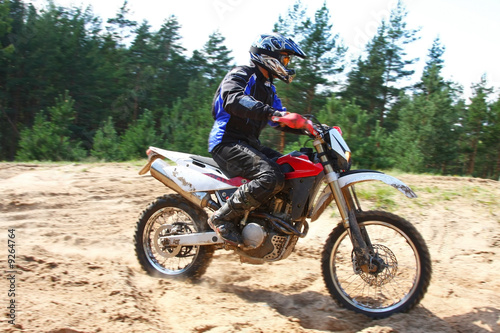 Man driving off-road motorbike in sand.
