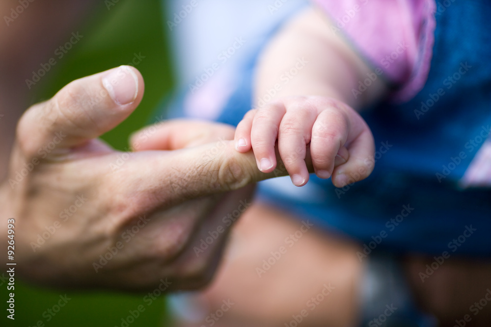 Babyhand auf Zeigefinger des Vaters. Sehr geringe Schärfentiefe!