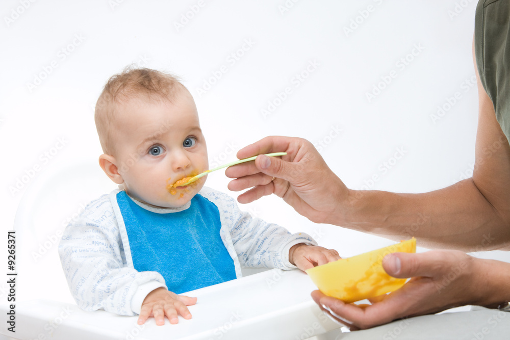 man feeding baby with a spoon, on bright background man feeding baby with a spoon, on bright background