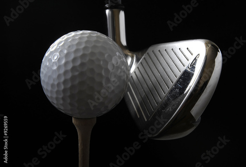 Golf club with ball on a tee in the black background