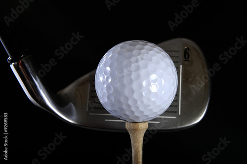Golf club with ball on a tee in the black background