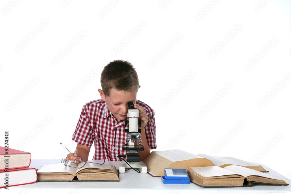 boy looking through a microscope and taking notes boy looking through a microscope and taking notes