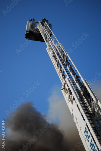 Ladder truck with fireman at top battles a blaze.