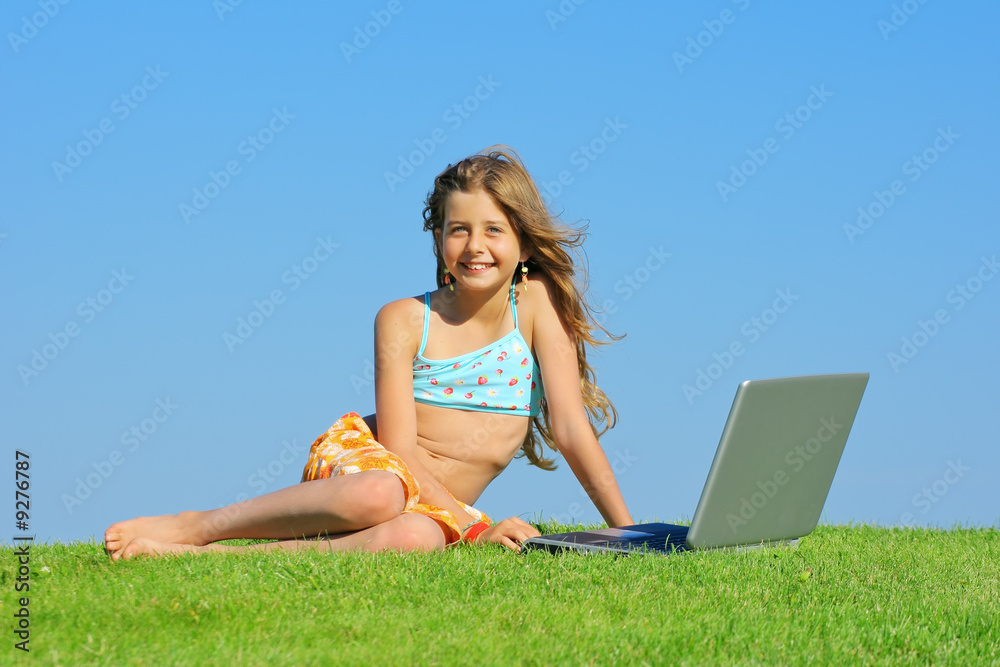 Jeune fille avec ordinateur portable dans l'herbe Jeune fille avec ordinateur portable dans l'herbe