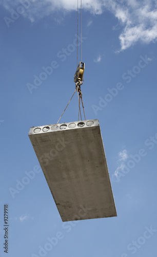 Hoisting crane lifts heavy concrete grey slab