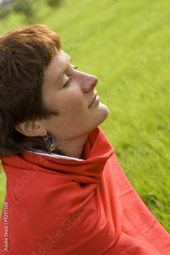 closeup portrait of pretty redhead woman sitting on the grass