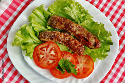 Grill sausage on leaves of salad with tomatoes
