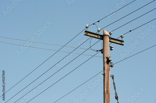 Old wooden electric pillar against clear blue sky