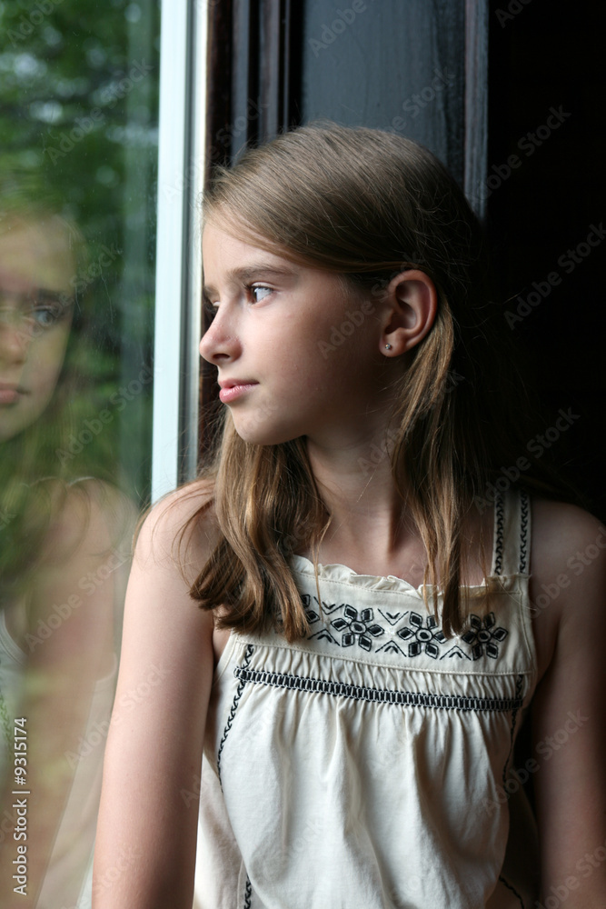 Fototapeta premium pretty girl looking out the window and seeing her reflection