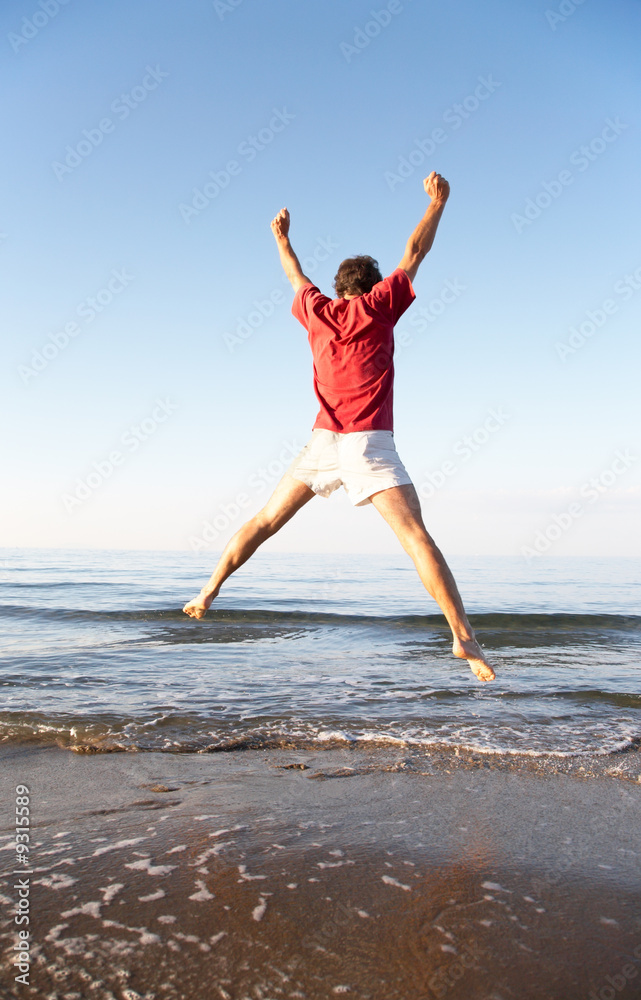 Back view of young man jumping on the beach Back view of young man jumping on the beach