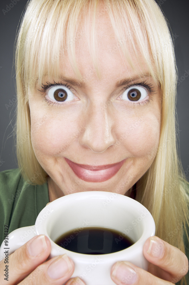 Beautiful Woman Enjoys Her Coffee Against a Grey Background. Beautiful Woman Enjoys Her Coffee Against a Grey Background.