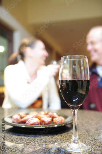A glass of red wine with a plate of dried dates.
