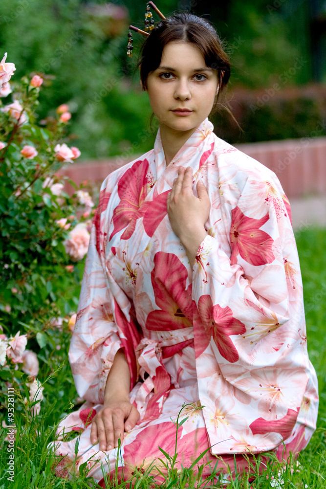 Girl in a pink yukata near rose-bush.